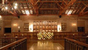 Zona de bar con vigas de madera, separador de vidrio estampado y varios taburetes de bar.