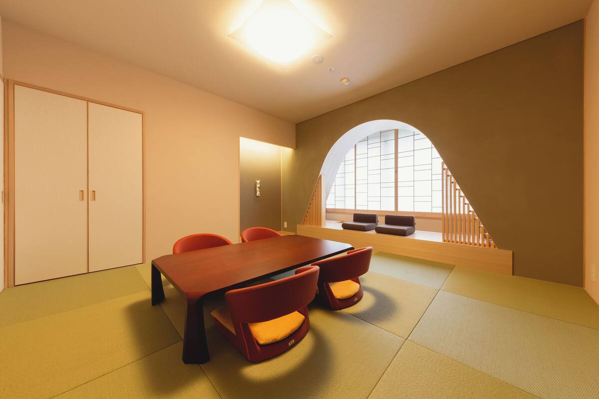 A conference room with a wooden table and red chairs, a sliding door, and a view through an arched window.