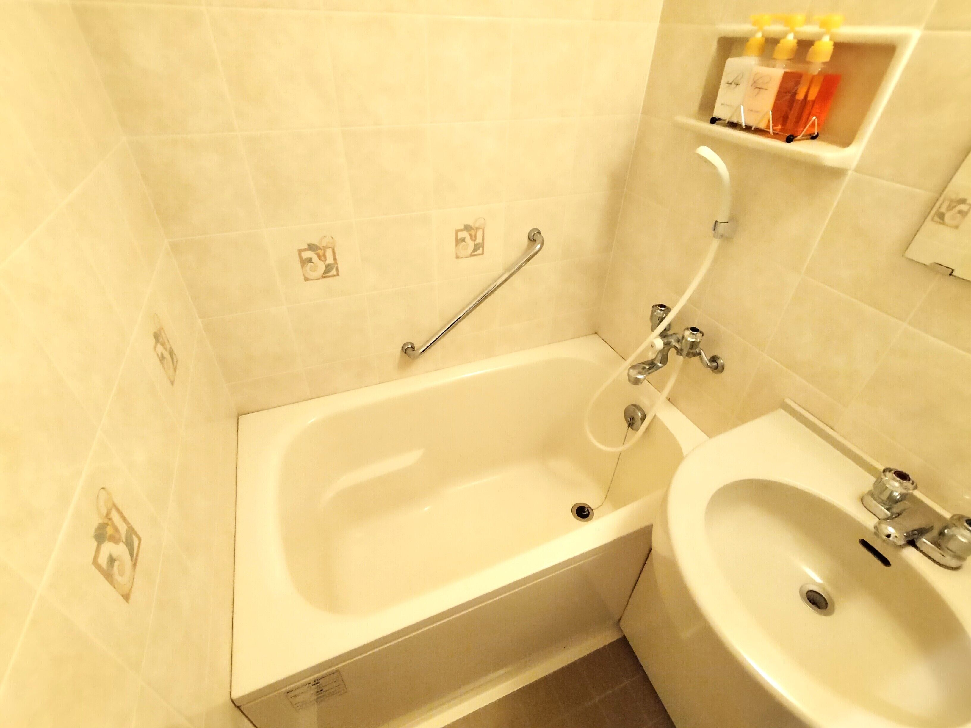 Un baño con bañera, lavamanos y estante con artículos de aseo.