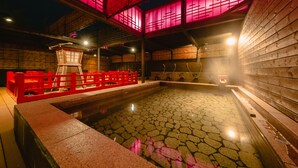 A traditional Japanese onsen with a stone hot spring, wooden walls, and red lanterns. - Arima Kirari (Kobe)