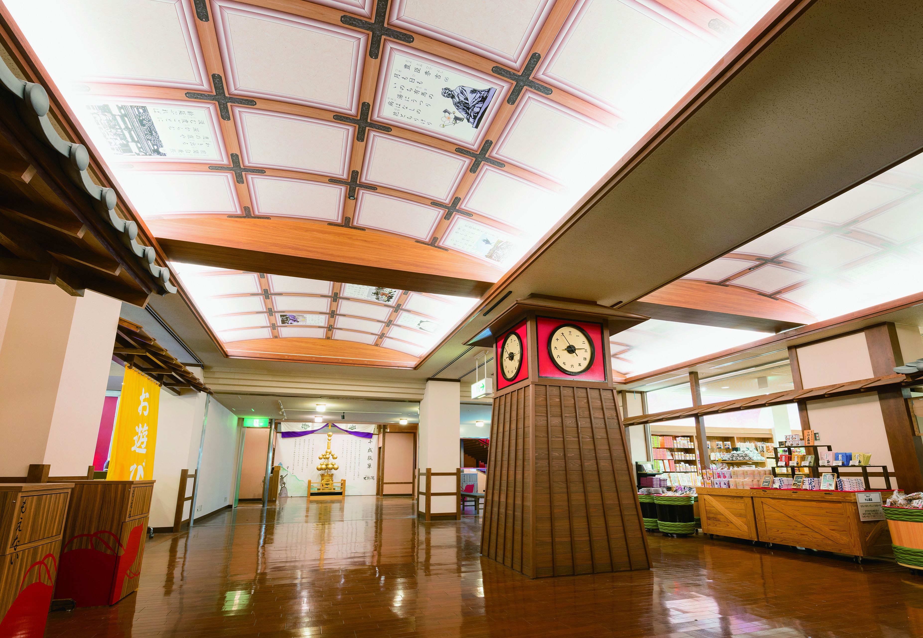 A spacious indoor area with a wooden floor, a central clock tower, and a ceiling with a grid pattern.