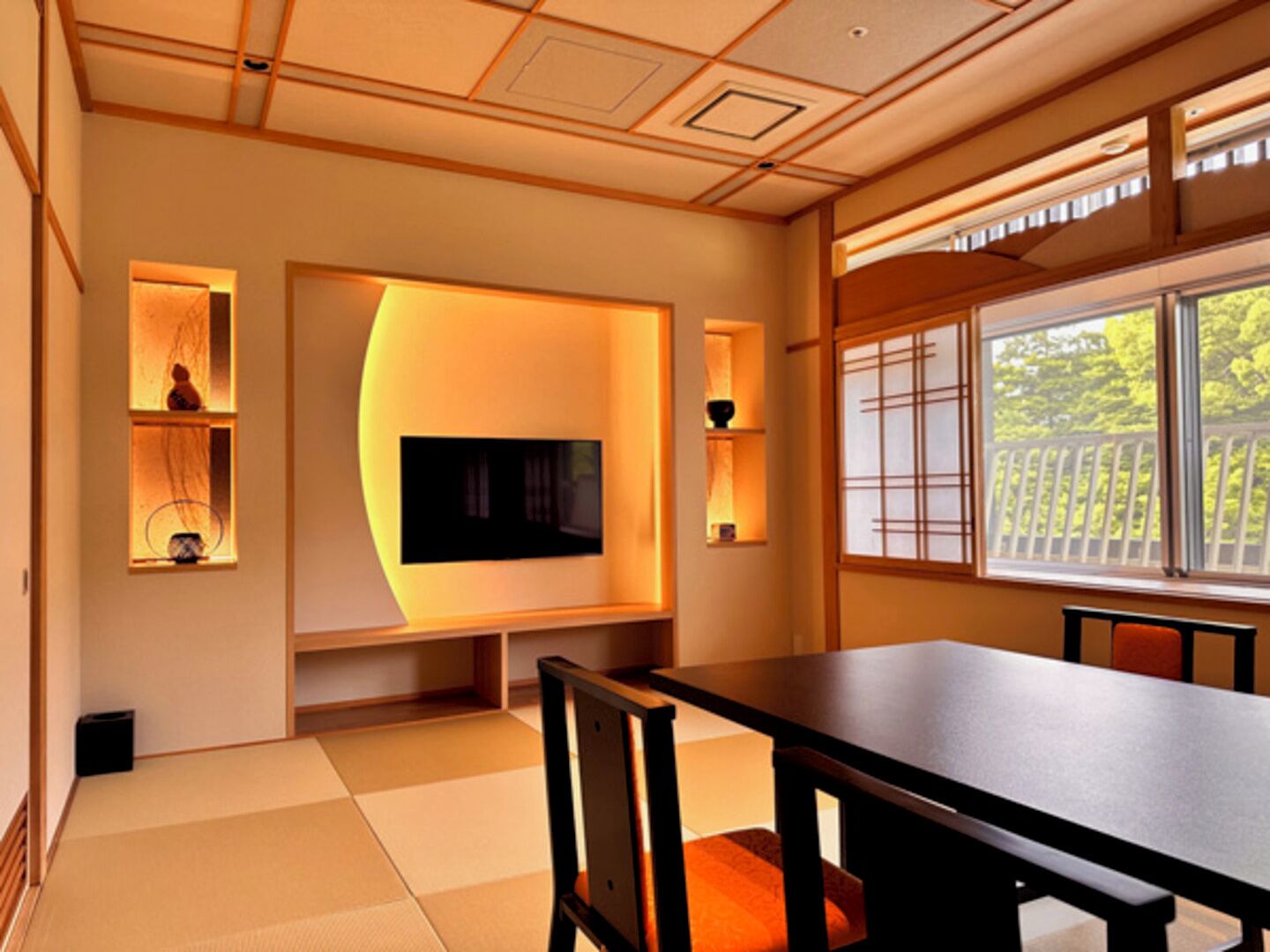 A traditional Japanese-style room with tatami flooring, a low table, and a television mounted on the wall.