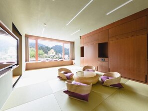 A modern room with tatami flooring, a large window with a view of mountains, and a wooden cabinet. - Arima Kirari (Kobe)