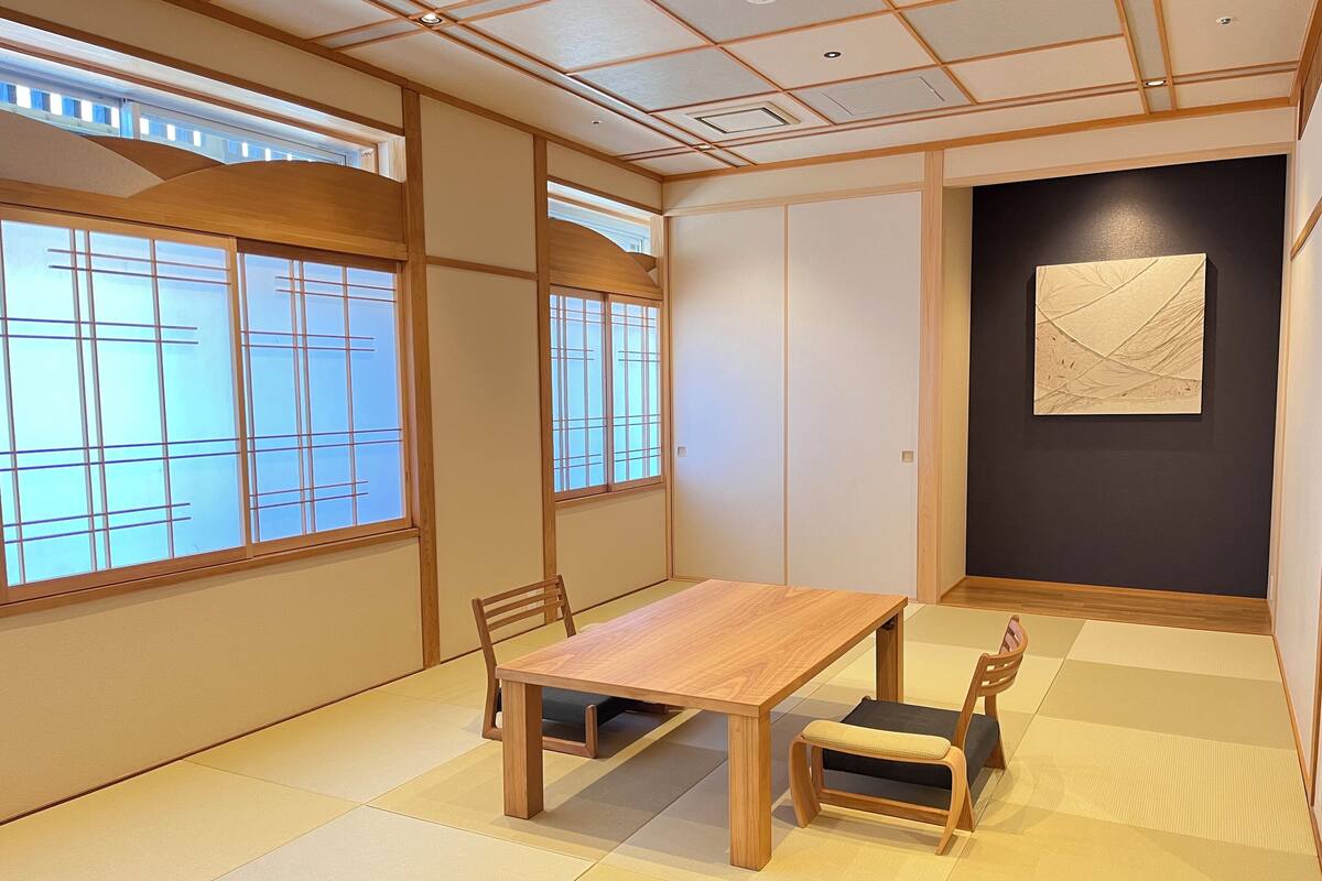 A traditional Japanese-style room with tatami flooring, a wooden table, and chairs.