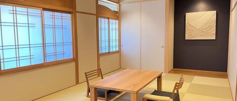 A traditional Japanese-style room with tatami flooring, a wooden table, and chairs.