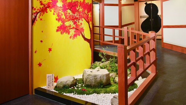 A traditional Japanese interior with a vibrant red maple tree mural, a wooden staircase, and a black sculpture. - Arima Kirari (Kobe)
