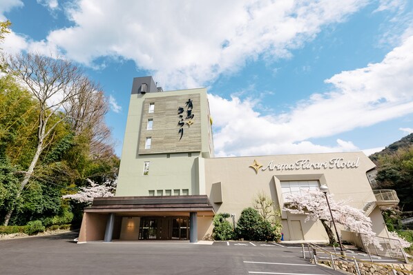 A hotel with a modern facade, a prominent sign, and a parking lot. - Arima Kirari (Kobe)