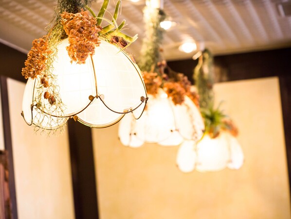 A chandelier with multiple spherical light fixtures, each adorned with dried flowers and greenery.