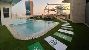 A rooftop pool area with a view of a city skyline, lounge chairs, and a Heineken winner sign. - Ramee Grand Hotel & Spa (Manama)