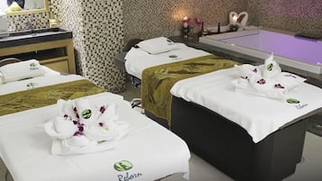 Relax in a serene spa room with three massage tables, a large bathtub, and a self-service area.