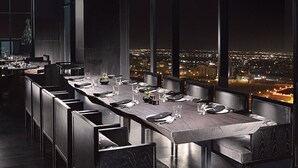 A modern dining area with a long table, dark chairs, and pendant lighting. - Ramee Grand Hotel & Spa (Manama)