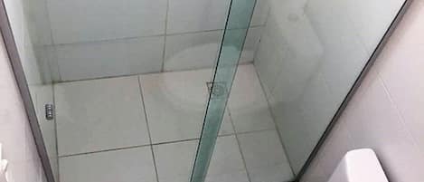 A small, enclosed shower stall with a glass door, a toilet, and a bidet.