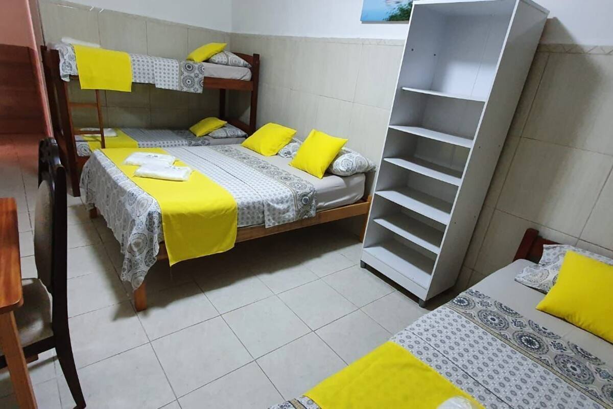 A dormitory room with bunk beds, a desk, and a shelving unit.