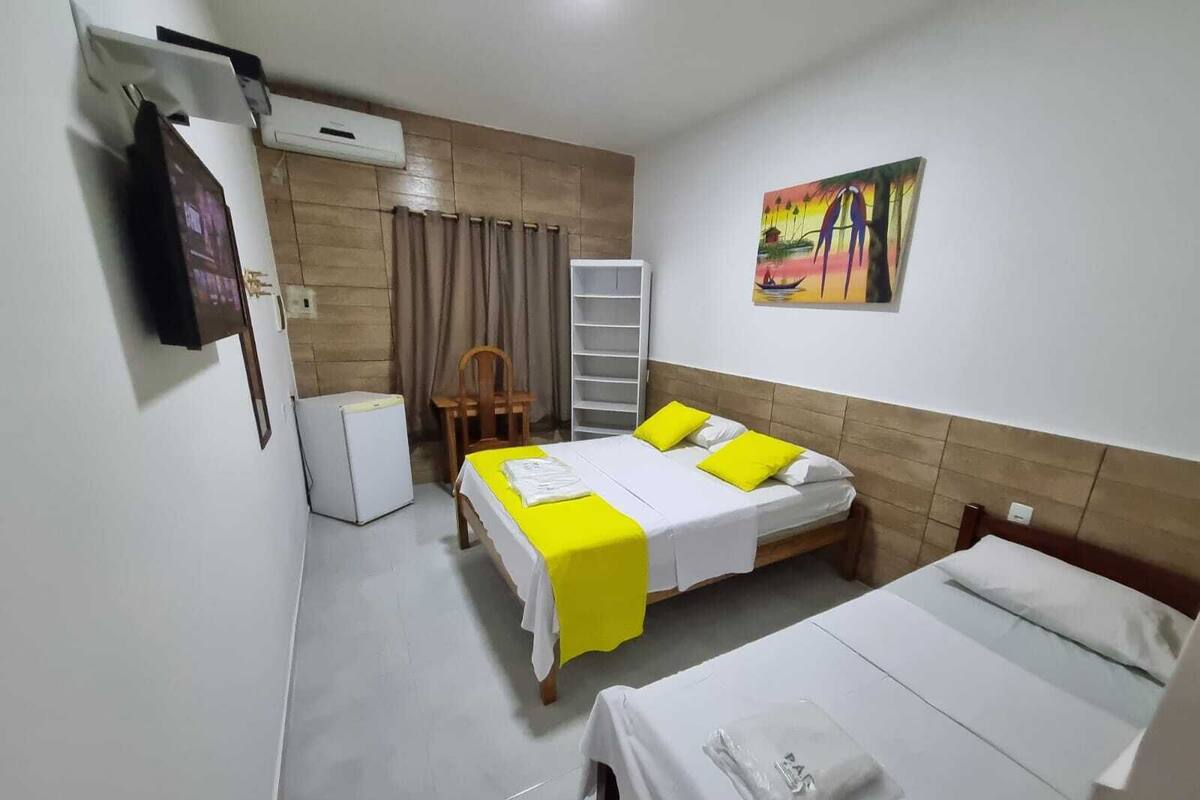 A hotel room with two beds, a TV, a refrigerator, and a painting on the wall.