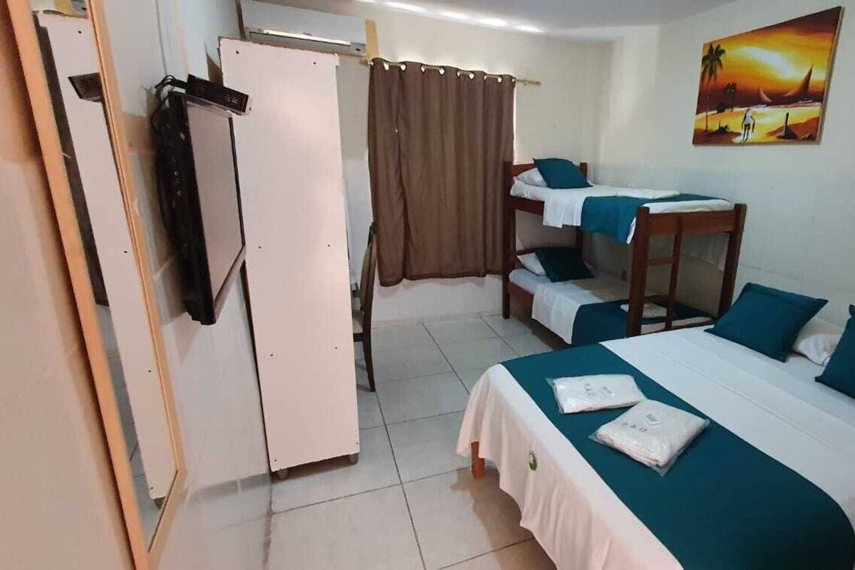 A room with a bunk bed, a desk, and a chair. There is a curtain, a painting on the wall, and a door.
