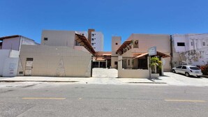 Un edifici amb una entrada tancada per reixa, una placa i un cotxe aparcat.