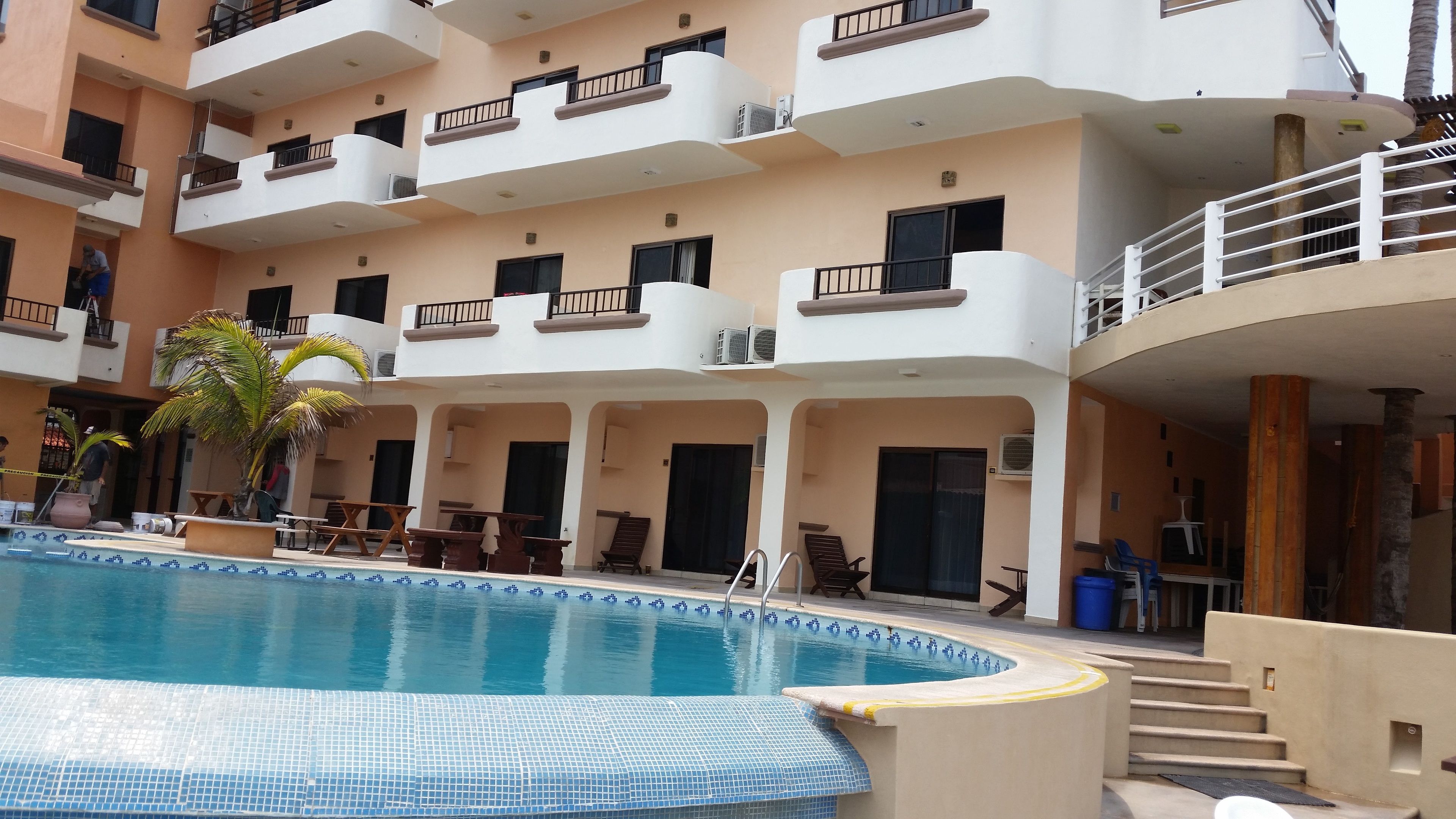 A multi-story hotel with a swimming pool, outdoor seating, and balconies.