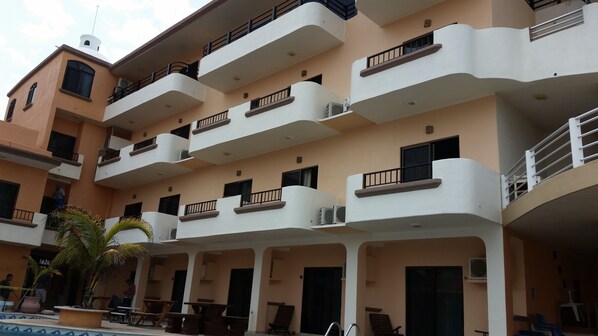 Un edificio de varios pisos con balcones, unidades de aire acondicionado y zonas de estar al aire libre.