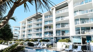 Um hotel moderno com várias varandas, piscina e espreguiçadeiras.