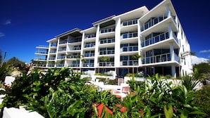 A multi-story hotel with balconies, outdoor seating, and lush greenery.