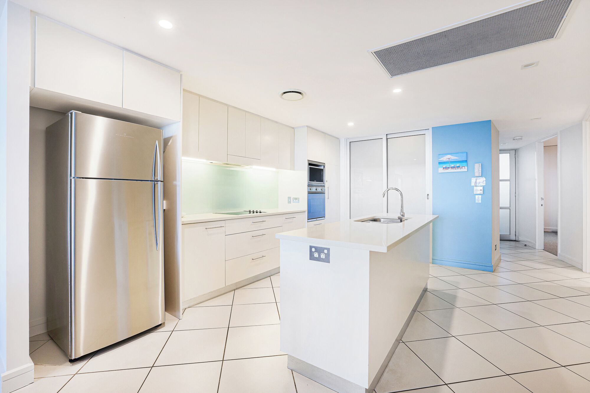 Una cocina moderna con electrodomésticos de acero inoxidable, una isla central y una pared de acento azul.