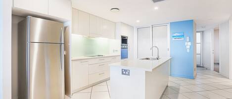 Una cocina moderna con electrodomésticos de acero inoxidable, una isla central y una pared de acento azul.