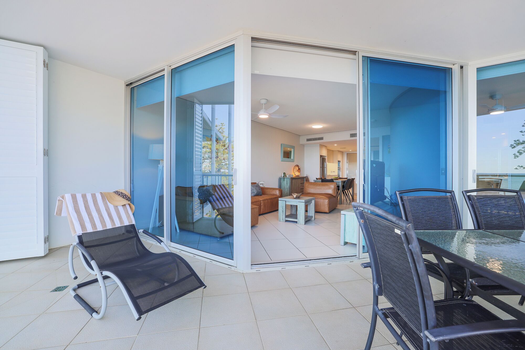 A modern living room with a glass door leading to a balcony, furnished with a sofa, chairs, and a table.