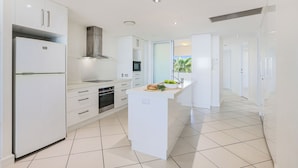A modern kitchen with white cabinetry, a central island, and a view of the outdoors.