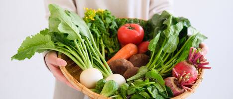 Una persona sostiene una cesta llena de verduras y huevos.