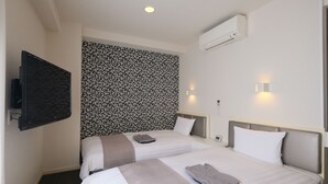 Una habitación de hotel con dos camas, un televisor de pantalla plana, aire acondicionado y una pared con diseño.