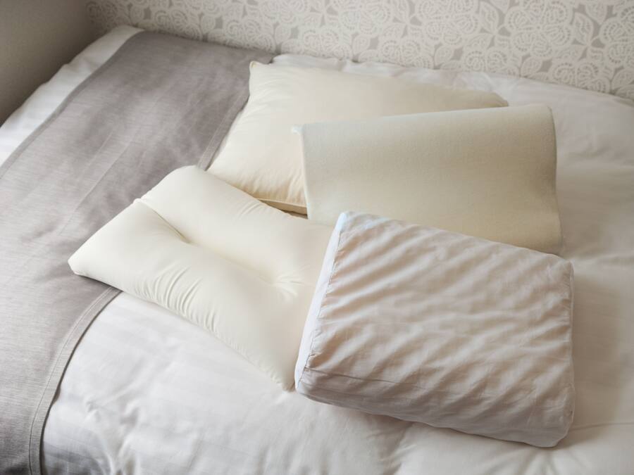 A bed with white bedding and a patterned wall.