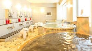 Un baño moderno con varios lavamanos, espejos y una bañera de hidromasaje grande.
