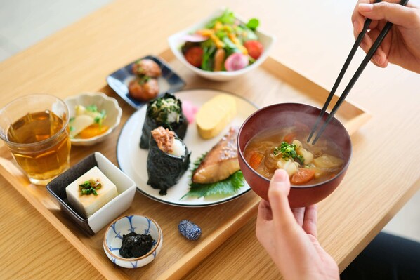 A tray with various Japanese dishes including sushi, a bowl of soup, and a small bowl of pickled vegetables.