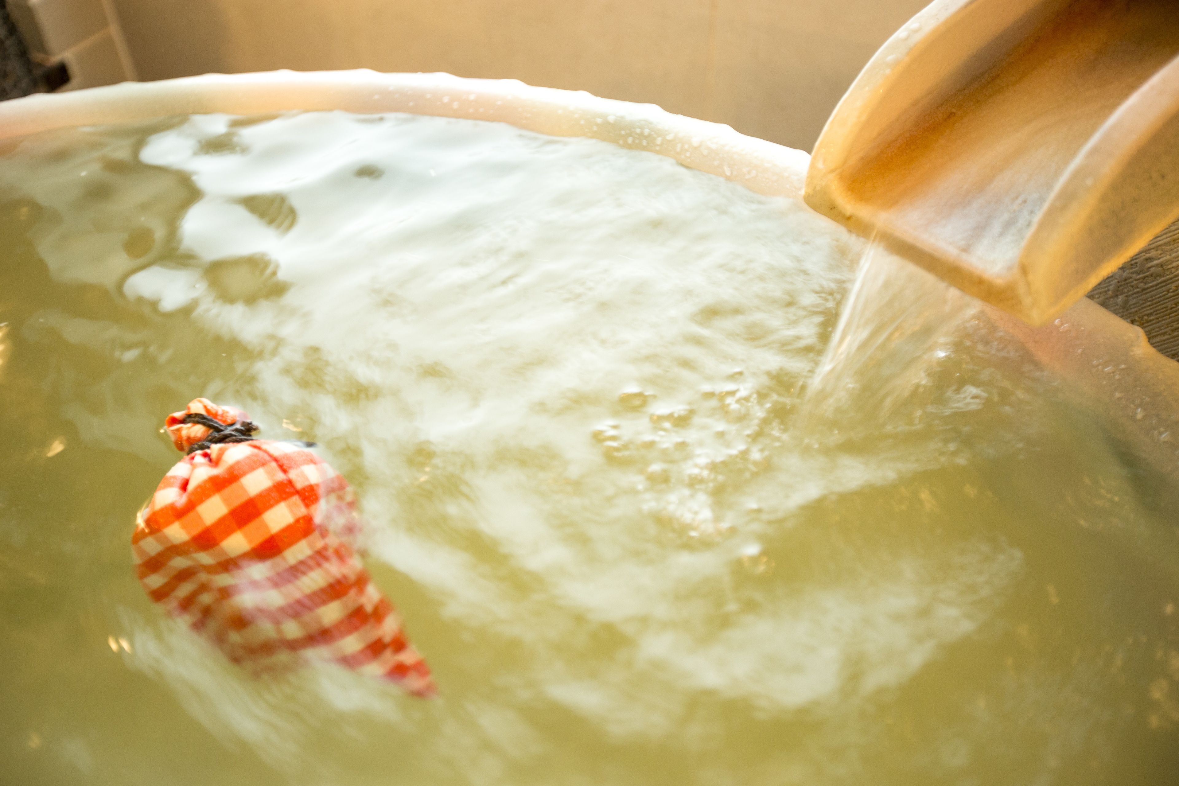 A bathtub with a person in a checkered bathrobe.