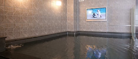 Una piscina con pared de azulejos y televisor montado.