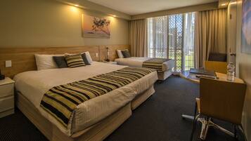 A hotel room with two beds, a desk, and a chair.