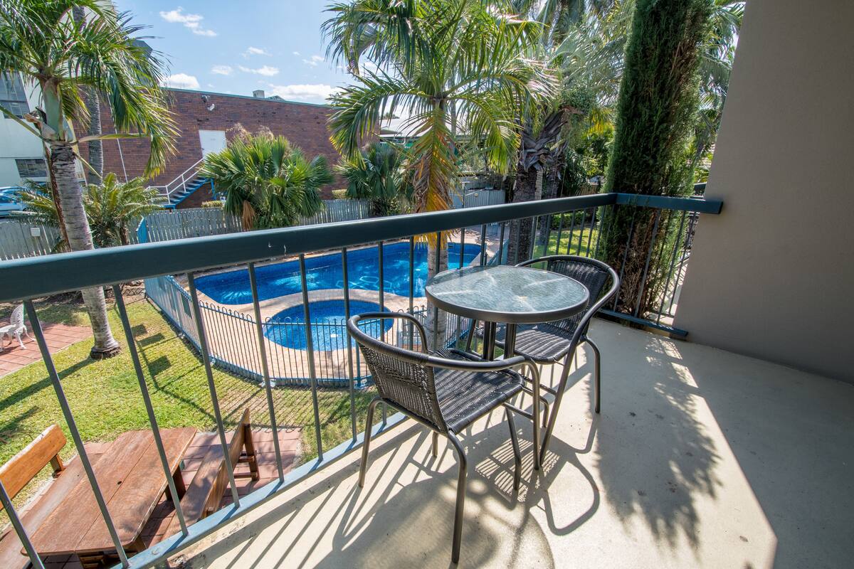 A balcony with a pool, chairs, and a table.