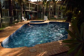 A swimming pool with a tiled edge, surrounded by a brick patio and a fence. - Motel 98 (Rockhampton)