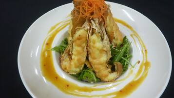 A plate with food, including what appears to be fried items and greens, with a sauce drizzled around.