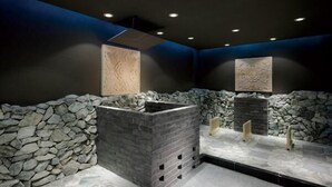 Une salle de bain moderne avec des murs en pierre, un lavabo central et des éléments décoratifs.