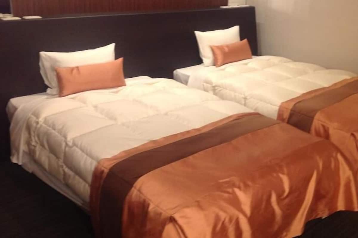 A hotel room with two beds, each with white bedding and brown headboards.