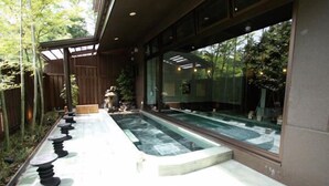 Un espace piscine extérieur moderne, doté d’une terrasse en bois, de marches en pierre et offrant une vue sur la verdure environnante.
