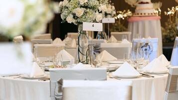 A banquet hall with round tables, white tablecloths, and floral centerpieces.
