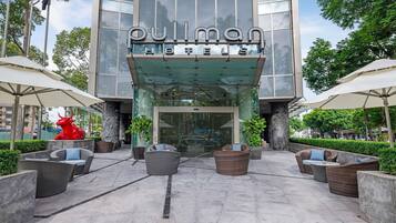 A hotel entrance with a glass facade, outdoor seating, and a red bull sculpture.