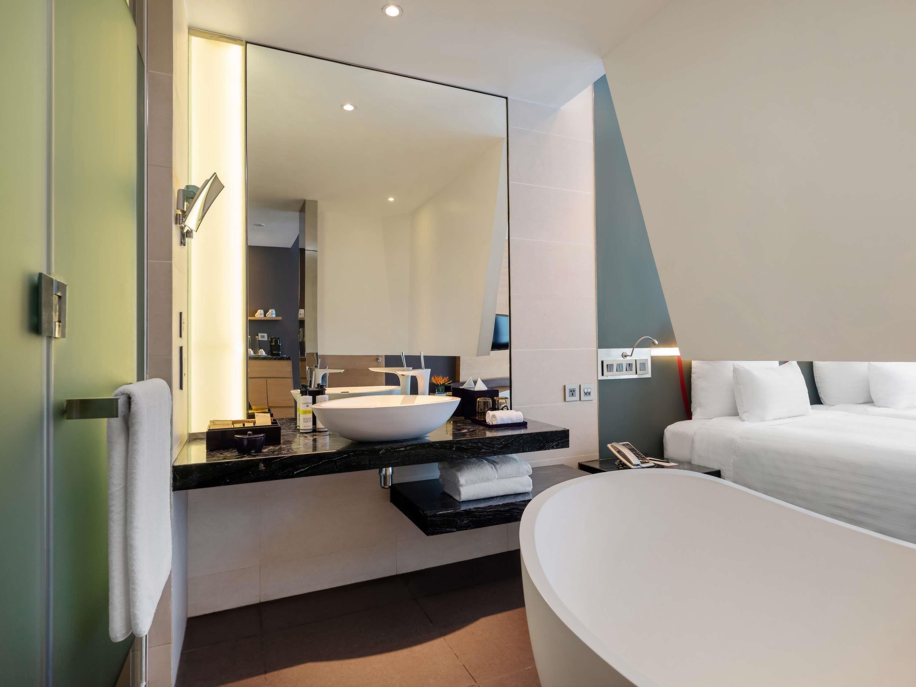 Un baño moderno con una bañera grande, un tocador con lavamanos y un espejo.