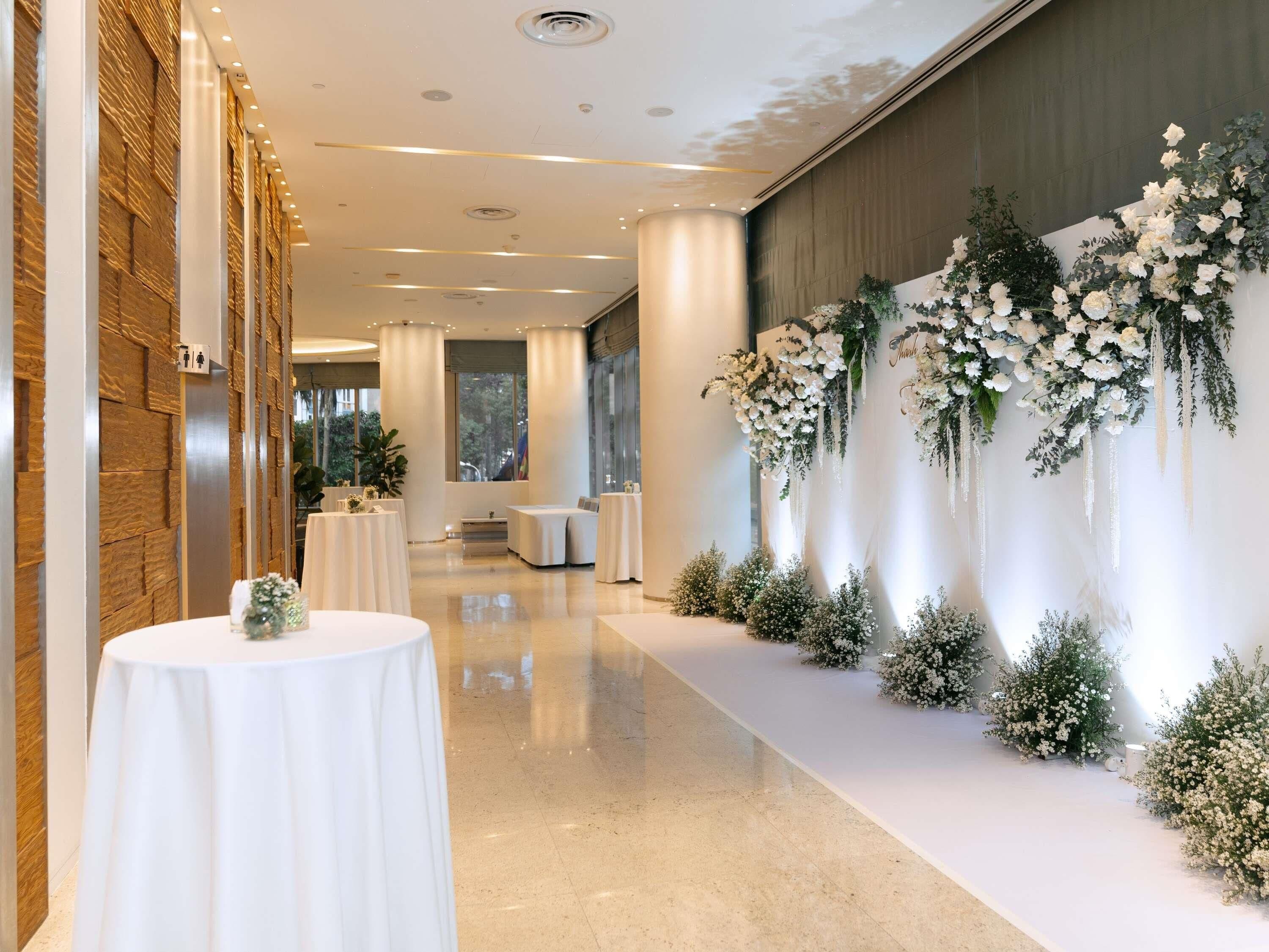 A corridor with round tables, a floral wall decoration, and a view of the outdoors.
