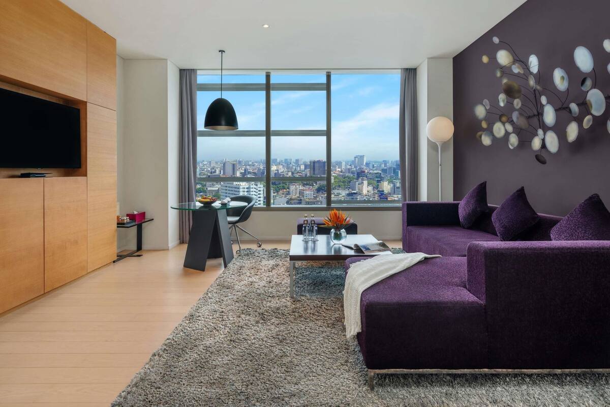 Ein modernes Wohnzimmer mit Stadtblick, einer Couch, einem Couchtisch und einem an der Wand montierten Fernseher.