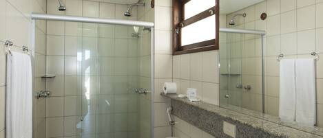 A modern bathroom with a glass-enclosed shower, a granite countertop, and a large mirror.