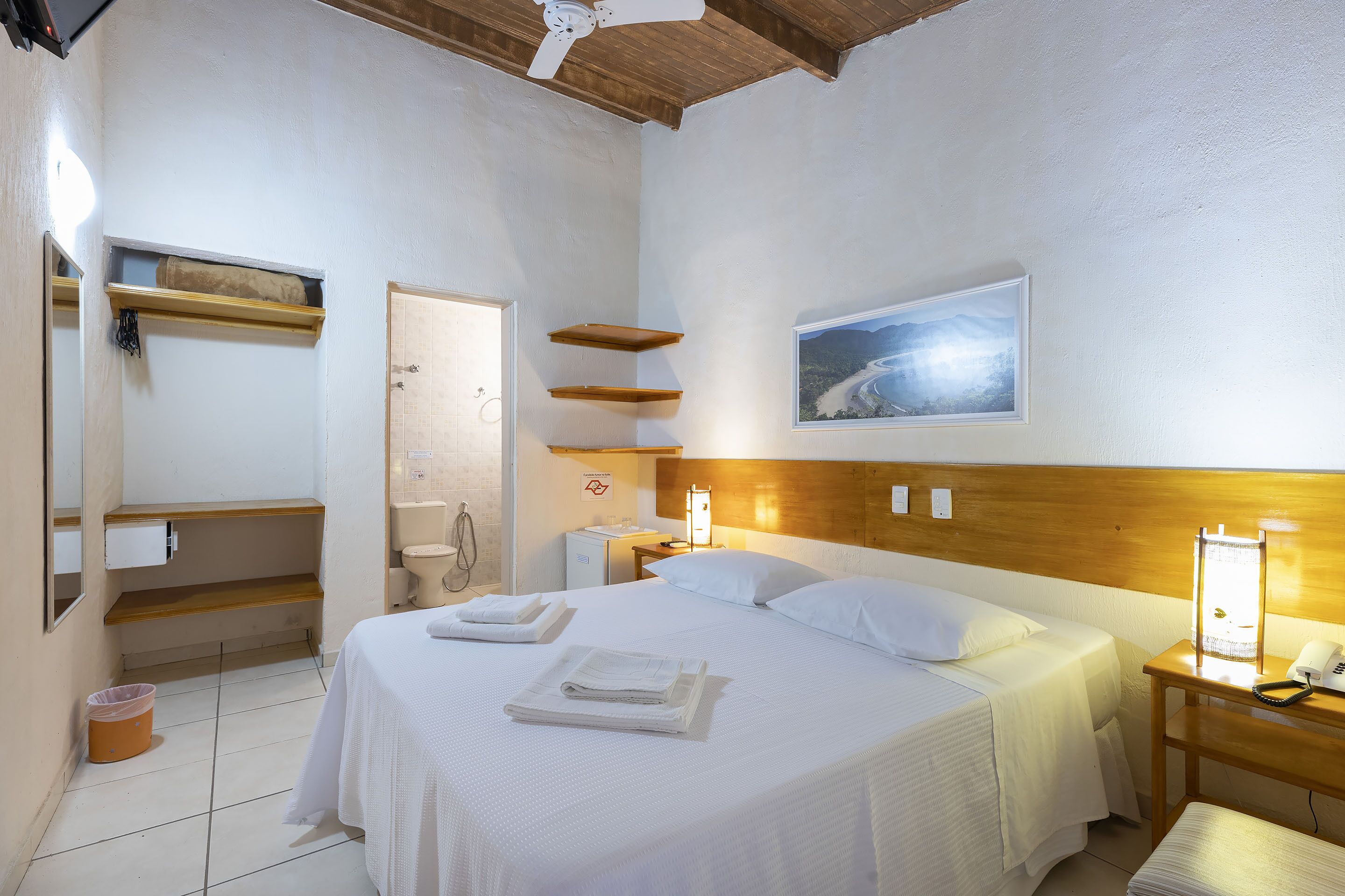Una habitación de hotel con cama, mesita de noche y un cuadro en la pared.