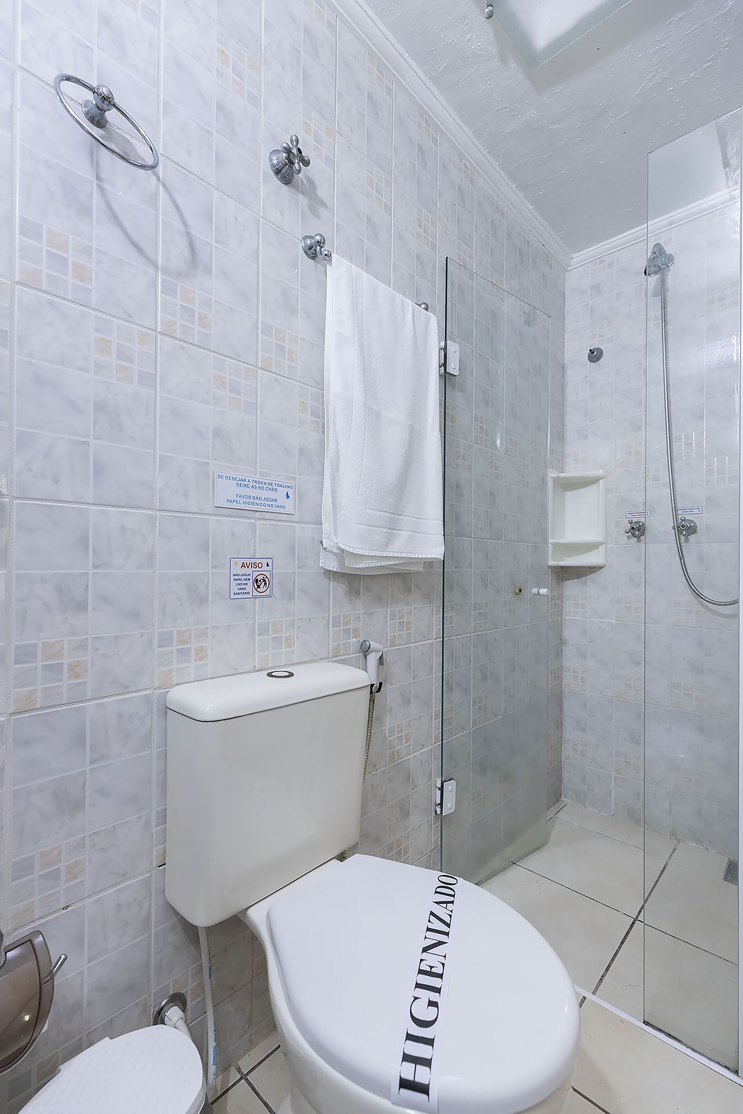 A bathroom with a toilet, a shower, and a glass-enclosed shower stall.